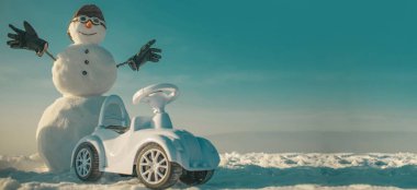 Kardan adam şoförü karlı arka planda arabanın yanında. Kardan adamla Noel afişi. Yeni yıl tebrik kartı ile kardan adam