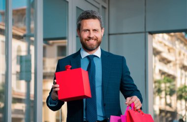 Harika bir hediye. Elinde hediye kutusu olan ve şehrin karşısında dururken gülümseyen adam