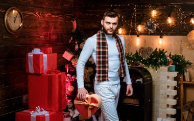 Hediye kutusu sürprizi olan yakışıklı bir adam geceyarısını bekliyor. İyi tatiller. Hediye kartı konsepti. Mutlu yıllar. Noel arifesi. - Eve. Noel hediyeleri. Noel kutlaması gelenekleri