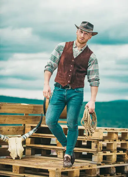 Amerikalı kovboy. Yakışıklı vahşi batılı adam. Arka planda kement ipi olan kovboy.