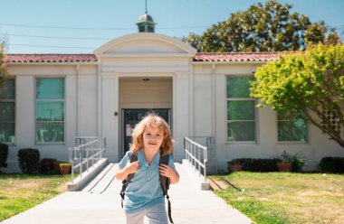 Mutlu gülümseyen çocuk okula gidiyor. Çantalı çocuk ilkokula gidiyor. İlkokul. Öğrenci git sırt çantasıyla çalış.
