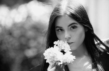 Çiçek parkının yakınında genç bir kadın. Bahar kızı. Bahar çiçekli ağaçtaki kadın. Açık havada çiçekli, yaz tarzı kıyafetli güzel bir kadın. Bahar güneşi parkı. Kokudan hoşlanan güzel bir kadın