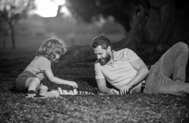 Dışarıda mutlu bir aile. Baba ve oğul sonbahar bahçesinde satranç oynuyorlar. Aktif insanlar parkta satranç oynayıp eğleniyorlar, çocuklarla vakit geçiriyorlar.