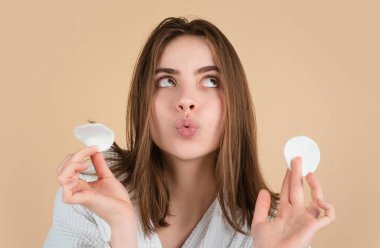 Günlük cilt bakımı prosedürleri olan genç ve güzel bir kız pamuk disk sünger pedi kullanarak yüz derisini doğal losyonla temizliyor. Temiz tenli, güzel genç bir kadın.