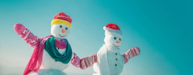 Dışarıda el ele tutuşan iki kardan adam. Dışarıdaki kardan adam arka planda. Kardan adamla Noel afişi. Yeni yıl tebrik kartı ile kardan adam