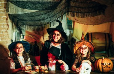 Cadılar Bayramı partisinde gülümseyen çocuklar. Komik çocuklar cadı kostümü giymiş. Şeker ya da şeker. Cadılar Bayramı partisi sırasında eski evde korku hikayeleri okuma korkunç kostümleri Sevimli çocuklar