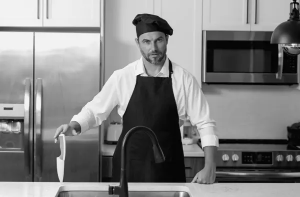 stock image Portrait of chef man in a chef cap in the kitchen. Man wearing apron and chefs uniform and chefs hat. Character kitchener, chef for advertising