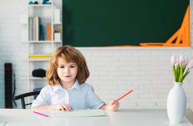 Sınıfta ders sırasında ödev eğitimi alan şık bir okul çocuğu, eğitim konsepti, sevimli bir okul öğrencisi.