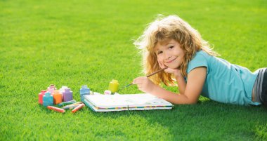 Çocuk çizimi. Okul çocukları yaz parkında resim çiziyor, resim yapıyor. Küçük ressam açık havada resimler çizer.