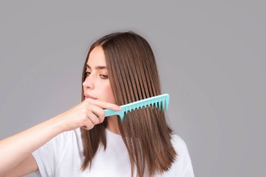Güzel bir kadın sağlıklı saçlarını tarıyor. Sağlıklı, uzun, düz kadın saçı, yakın çekim.