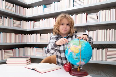 Okul ve öğrenciler sınıfta. Eğitimli çocuklar. Okul sınıfındaki zeki çocuk öğrenci seni. Okuma ve öğrenme konsepti. Okul çocuğu kütüphanede, okul malzemelerinin yanında. Çocuk coğrafya öğreniyor