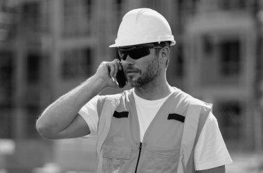 İspanyol 40 'ların işçi inşaatçısı inşaat alanında. Amerikalı orta yaşlı erkek işçi. Çalışanlar telefon kullanıyor, inşaatçılar işe ara veriyor. Cep telefonlu mimar