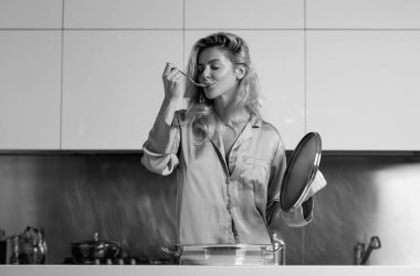 Taste and delicious. Blond beautiful sexy girl cooking in kitchen doing breakfast with healthy food. Morning of pretty woman housewife