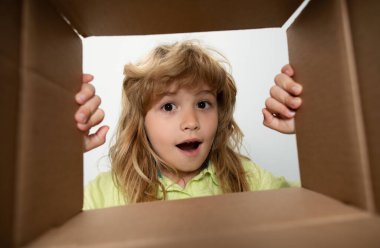 Şaşkın çocuk paketleri açıyor ve karton kutuyu açıp sürpriz bir yüz ifadesiyle içeri bakıyor. Paketleme veya açma kavramı