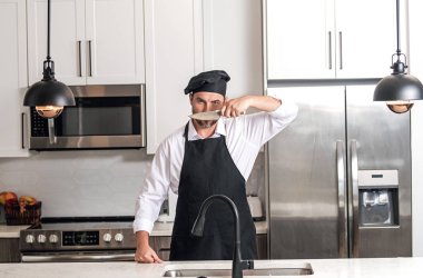 Aşçı aşçı adam. Milenyum aşçı üniformalı erkek şef. Aşçı mutfakta yemek pişiriyor. Aşçı şapkalı ve önlüklü