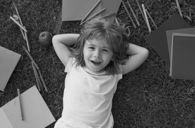 Çimlere, açık havaya ve manzaraya uzanmış sevimli bir öğrencinin portresi. Okul rüyası. Hayalperest okul çocuğu. Hayaller ve hayal gücü. Hayalci okul çocuğu suratı.