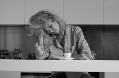 Mutfakta bir fincan kahveyle üzgün genç bir kadın. Kahve içen üzgün bir kız. Kötü haberlerle dolu mutsuz bir sabah.