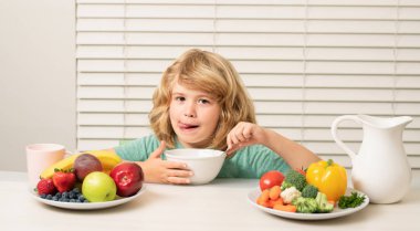 Müsli tahıl gevreğiyle sabah atıştırması. Çocuk öğle yemeği sırasında mutfakta sebze ve meyve yiyen ergen bir çocuk. Sağlıklı yemek, çocuklar için sebze yemeği.