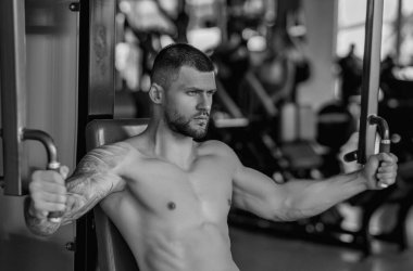 Muscular men lifting weights. Powerful male fit model doing workout in gym. Man lifting dumbells, strong athletic fit man doing exercises with dumbbells. Weightlifting workout. Fitness workout