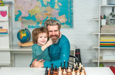 Çocuk, eğitim konsepti için satranç stili düşünüyor ya da plan yapıyor. Erkek öğretmen anaokulu çocuğuyla satranç oynar