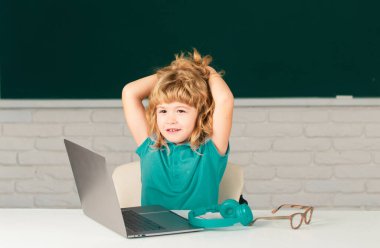 Okul çocuğu masa başında oturarak internetten e-öğrenim amaçlı internet kullanmayı öğreniyor. Eğitim ve bilgi modern teknoloji konsepti. Öğrenci dinleniyor ve dersten sonra dinleniyor.