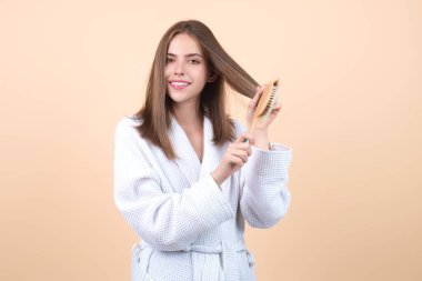 Beautiful model girl with comb brushing hair. Beauty woman with straight hair on studio background. Woman holding hairbrush near face. Healthy hair. Hairstyle and hair care concept. Shiny hairs