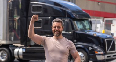 Kamyon şoförü. CDL. Kamyonun yanında erkek sürücü var. Kamyon şoförü. Milenyum kamyoncusu. Kamyon sahibi. Ulaşım endüstrisi araçları. Kamyonun önünde poz veren yakışıklı bir adam.