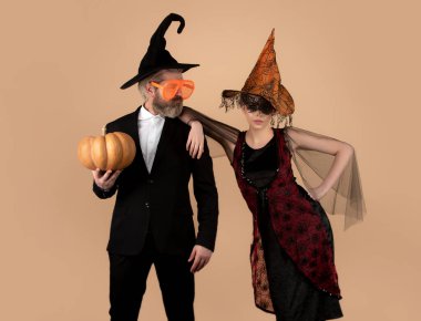 Funny couple with Halloween pumpkin. Portrait of Man and Woman in Halloween hat with pumpkin. Trick or treat. Scary hipsters couple in Halloween hat. Couple with witch hat hold pumpkin. Funny clipart