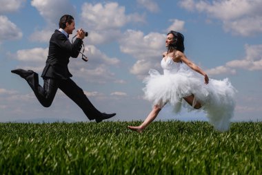 Düğün çifti gelin ve damat doğada. Birbirine aşık çiftler, evlilik töreni ve etkinlik. Kutlama düğünü. Genç gelin ve damat çiftleri. Komik çılgın düğün çifti zıplıyor