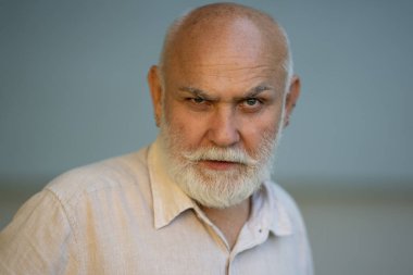 Gri saçlı ve beyaz sakallı yaşlı bir adam. Sakallı kıdemli adam. Sakallı yaşlı adamın yüzü. Kel emeklilerin vesikalığı, emekli konsepti. Gri sakallı, olgun, yaşlı bir adamın yakın plan portresi.