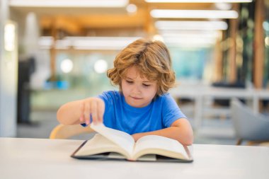 Çocuk kitabı okuyor. Halk kütüphanesinde kitap okuyan bir çocuk. Çocuklar erken öğrenim ve eğitim kavramı