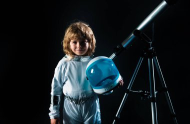 Astronot başlığı ve teleskop takan küçük bir çocuk. Astronotun içinde oynayan ve uzay adamı olmayı hayal eden sevimli bir çocuk. Astronomi ve astroloji kavramı