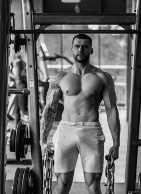 Motive olmuş erkek sporcu spor zinciri ile egzersiz yapar, vücut geliştirme egzersizi yapar. Güçlü kaslı adam spor yapıyor. Spor ve sağlıklı yaşam tarzı kavramı. Zincirli kaslı adam.