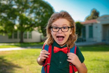 Portrait of excited pupil with backpack near school outdoors clipart