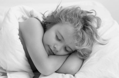 Sabah uykusu. Sarışın, beyaz bir çocuğun güzel yüzü, yatakta uyuyor. Tatlı rüyalar. Küçük bebek evde yatarken uyuyor.