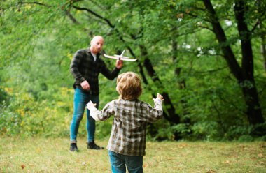 Babasıyla oyuncak uçakla oynayan tatlı bir çocuk. Babalar Günü. Baba ve oğlu dışarıda oyuncak uçak oynuyorlar.