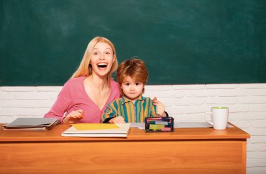 Okul çocuklarının portresi ve dersteki öğretmen. Öğretmen, genç öğrenciye derslerinde yardım ediyor.