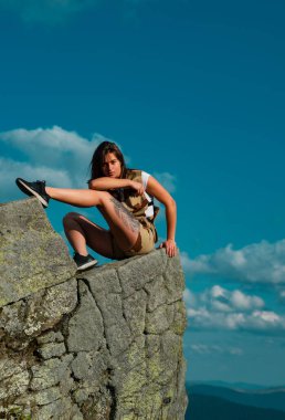 Hippi genç kız dağda günbatımının tadını çıkarıyor. Arka plandaki vadi manzaralı turist gezgini. Maymun Macerası