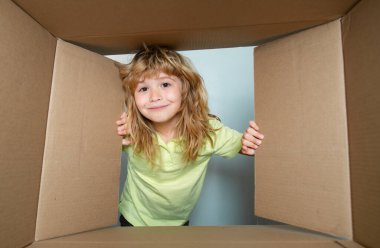 Heyecanlı çocuk kutuya bakıyor, karton kutu taşıyor. Paketler ve teslimat