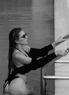 Beautiful young woman in a swimming pool, hot summer. Beautiful women relaxing at the luxury poolside. Female at travel spa resort pool. Summer luxury vacation