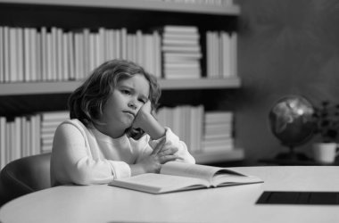 Yorgun okul çocuğu, okulda sıkılmış öğrenci. Kitabı olan bir öğrenci. Çocuk öğrenci bir kitapçıda ya da okul kütüphanesinde kitap okuyor. Çocuk okuması