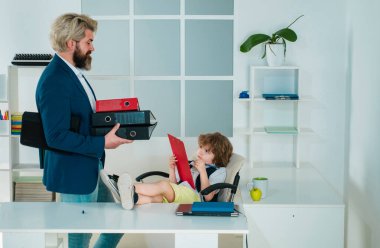 İş ortakları planları tartışıyor. Şirin çocuk ofis koltuğunda oturuyor kendinden emin büyük patron, komik iş adamı patronluk taslayan çocuk, yönetmen ve güçlü lider kavramı.