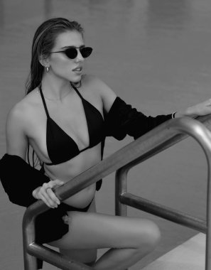 Fashion woman posing by the pool. Summer vacation. Sexy woman with slim sexy body in swimwear bikini relaxing in swimming pool spa. Vacation at luxury resort. Sexy girl in poolside