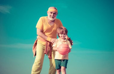 Büyükbabanı izle. Kıdemli fitness adamı ve oğlu mavi arka planda eğitim görüyor. Yaşlılık sağlığını gevşetmek için bir bahane değildir. Genç - eski çalışma