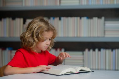 Okul ve eğitim kavramı. Kitap yığınıyla okul öğrencisi. Çocuklar okul kütüphanesinde kitap hikayesinin keyfini çıkarıyorlar. Çocukların hayal gücü, edebiyata olan ilgisi. Zeki çocuklar.