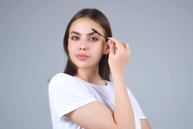 Koyu kaşlı güzel bir kadın kaş fırçası tutuyor. Kaş kaplaması. Güzellik prosedürlerini uygula. Kaş ve kaş çizgisi, kaş çizgisi.