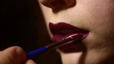 Makyöz ruj sürüyor. Yüzü, güzel bir kızın makyaj malzemeleri. Dudaklarda moda ruju. Profesyonel makyaj ruju. Profesyonel makyöz dudaklarını onunla boyar.