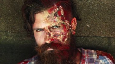 Cadılar Bayramı. Zombi adam. Kanlı yara izleri olan ürkütücü bir adam. Cadılar Bayramı 'nda yüzünü kapatıyor. Yüzü kanlı zombi adam. Cadılar Bayramı için yaratıcı sanat makyajı. Adam korkunç zombiyle yüzleşiyor. Cadılar Bayramı partisi