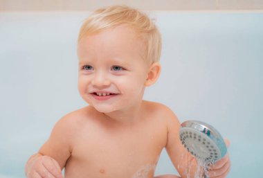 Gülümseyen çocuk oyuncak ördek ile banyoda. Banyo duş altında evde bebek boy gülümseyerek. Küçük çocuk yıkanmasında içinde banyo