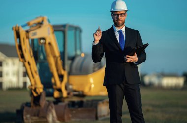 İnşaat alanında mimar. İnşaat alanında kask ve takım elbiseli mimar. İnşaatta duran kendine güvenen bir mimar. Yatırımcı ya da inşaat mühendisi. İspanyol 'un açık hava portresi